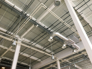 Ventilation pipes in silver insulation material hanging from the ceiling inside new building.