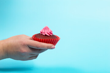 Cupcake as a gift. Cupcake in hand on blue background.