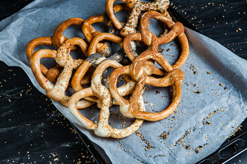Fresh prepared homemade soft pretzels. Different types of baked bagels with seeds on a black background.