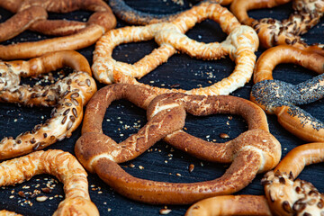 Fresh prepared homemade soft pretzels. Different types of baked bagels with seeds on a black background.
