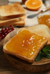 Delicious toasts with jam and mint on wooden table, closeup