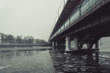 Bridge across the river, the ice on the water is broken, photo in winter