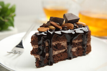 Piece of tasty homemade chocolate cake with nuts on plate, closeup