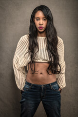 Tall and Glamorous BIPOC woman with long hair poses in a Los Angeles studio in jeans and a cropped sweater.