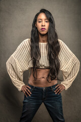 Tall and Glamorous BIPOC woman with long hair poses in a Los Angeles studio in jeans and a cropped sweater.