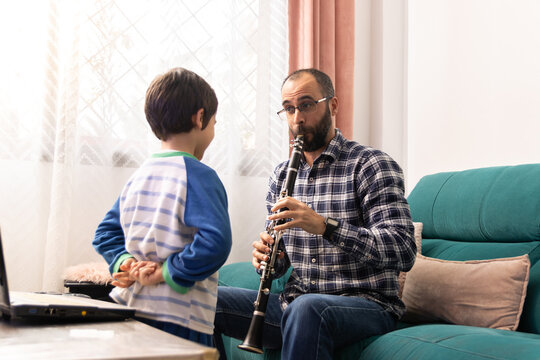 Father teaching his son to play the clarinet in the living room