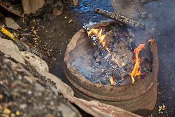 Cut iron barrel with fire inside and smoke.