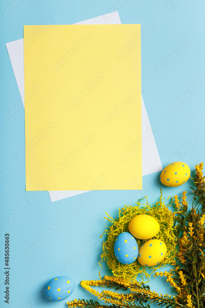 Poster easter composition. eggs flowers on a blue background. empty sheet of paper with space for text and 