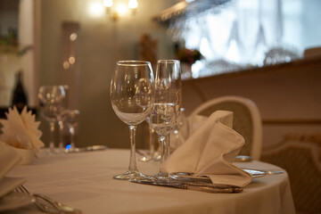 Beautifully served table with wine glasses and napkins on a white tablecloth in a restaurant