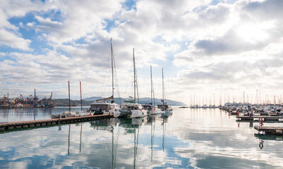 View from the shore to the sea harbor with moored ships under thick clouds with a blue sky peeking through them