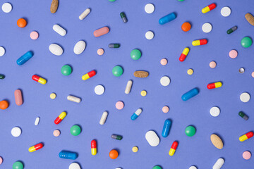 Medical background. Pattern made from Various small Pills on bright violet background. Flat lay, top view