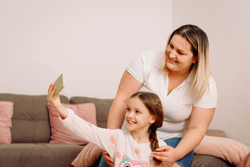 Mother and little dayghter have fun posing for self-portrait picture together enjoy playful weekend...