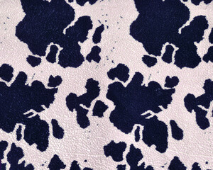 Graphic print on the skin of a cow on a dense, mass-produced upholstery fabric. Black spots on a beige background. Abstract drawing, background.