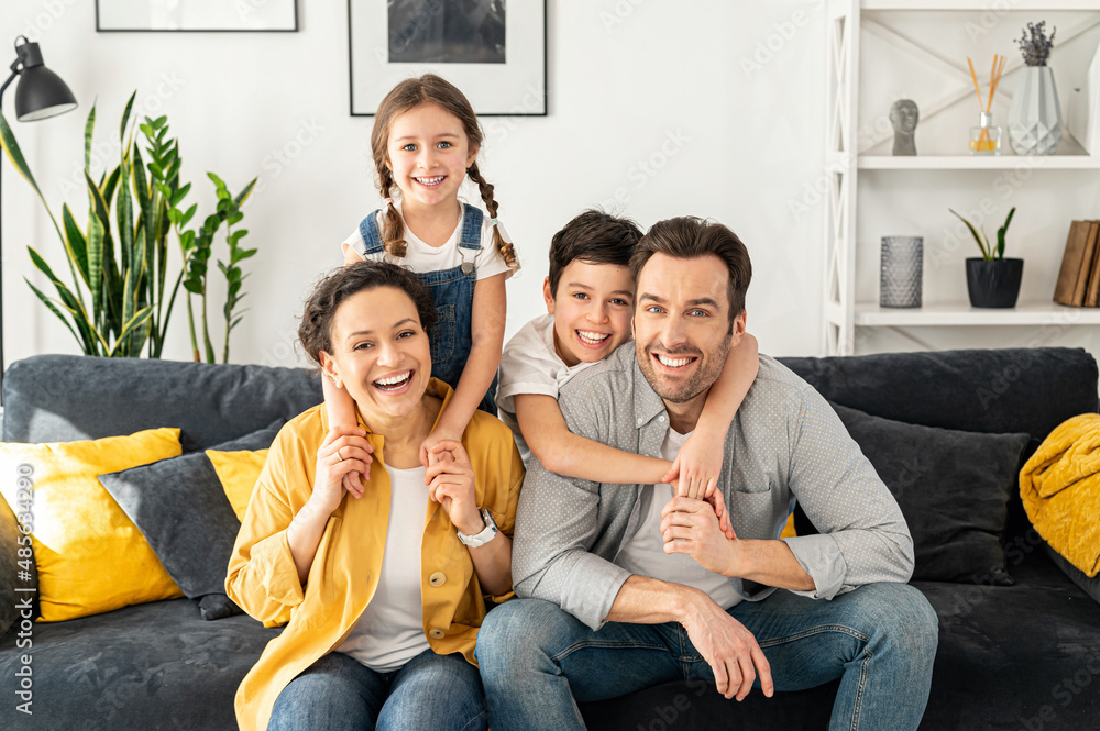 Wall mural happy together. portrait of cheerful multiracial family of four - mom, dad, son and toddler daughter