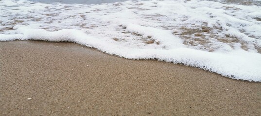Detail of small waves arriving at the shore of the beach. Relaxation and peace