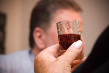 Hand einer Seniorin hält kleines Glas mit Schnaps in der Hand