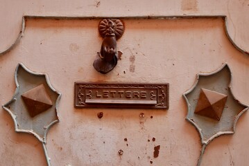 Old rusty door knocker in the shape of a hand and mail slot on red iron door. Marrakech, Morocco.