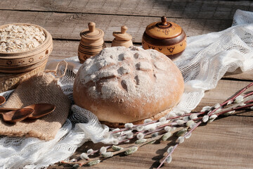 Fototapeta na wymiar A traditional set of bread, loaves and other wooden accessories. Round white rye bread. Wooden background. Wheat, willow branches, Easter holiday