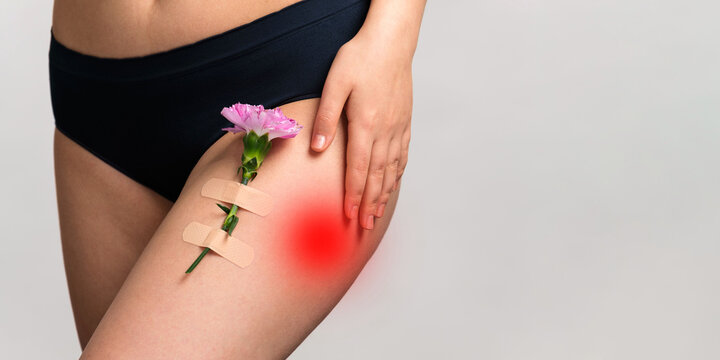 Cropped photo of beautiful woman hips wearing underwear feeling hips pain and holding her hand on it with carnation branch holded by adhesive plaster on the hip.