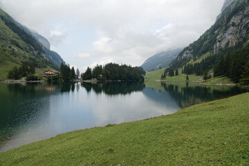berggasthaus seealpsee switzerland, big lake in total view, with island and restaurant hotel, cloudy summer day, mystical atmosphere