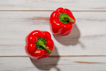 Two red sweet peppers on a wooden background. Light background. Food, vegetarian concept.