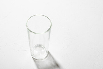Empty glass beaker on a white background. Clear shadow, hard light.