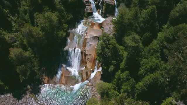 Toma a&eacute;rea de cascadas naturales pasando por rocas en medio de bosques.