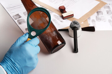 forensic expert using a magnifying glass examines fingerprints on evidence