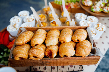 Fresh pastries in a coffee shop. sausage in dough Crispy bun with filling. healthy snacks Freshly baked croissants in a wooden basket. sweety and crispy desserts