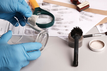 Forensic fingerprint analysis, criminalist collects latent fingerprints using fingerprint powder on...