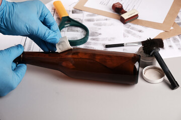 Forensic fingerprint analysis, criminalist collects latent fingerprints using fingerprint powder on...