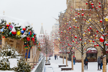 Moscow, Russia, February 7, 2022, fair on Red Square on a winter morning, it is snowing. Christmas street decorations. A beautiful image of New Year's Moscow, with people walking along the road 