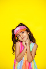 Funny little girl about 6 years old in casual summer clothes posing on a plain yellow background. The concept of a child's lifestyle. Layout of the copy space.