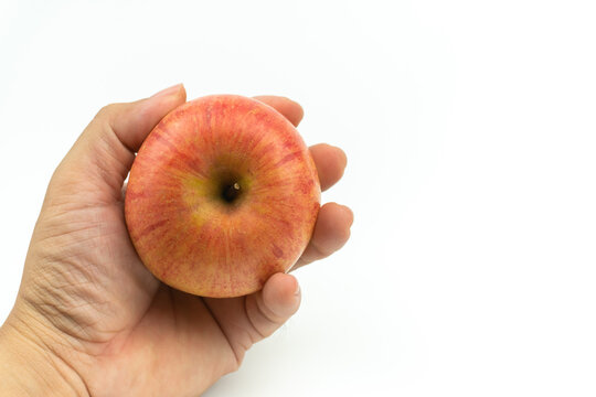 Man's hand holding an apple from the bottom left of the picture. isolated on a white background, space for text