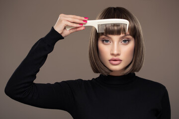 Portrait of a beautiful woman with a short haircut holding a comb in her hand. - 485639433