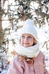 Funny little blonde girl of 7 years old in casual winter clothes posing outside in snowy weather . The concept of a child's lifestyle. Layout of the copy space.