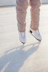 Funny little blonde girl of 7 years old in casual clothes posing on a skating rink in skates. The...