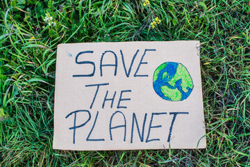 A Closeup Of A Sign That Says Save The Planet, On A Background Of Grass