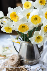 Bouquet of white daffodils in a silver teapot on a lace napkin, on table, springtime flowers in a vase close up, decoration concept