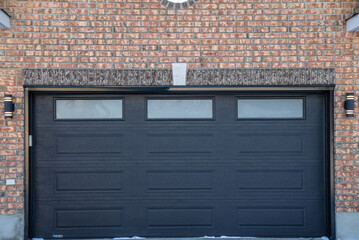 Exterior, dark steel garage door double width, three opaque windows, surrounded by brick wall and...