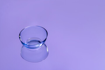 One contact lens on violet reflective surface