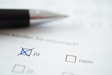 Ja: angekreuzter Stimmzettel mit Stift im Hintergrund