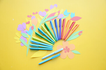 Bright notepads and colored pens on a background of colored paper. Writing accessories. Corporate gifts for office employees. Sunny mood for work.