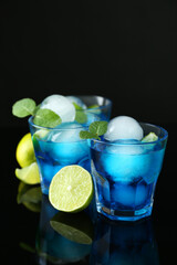 Delicious cocktails with ice balls, mint and lime on black background