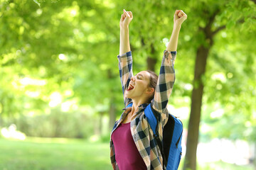 Excited student raising arms celebrating in a park