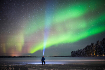 Person under Northern Lights display (aurora borealis) having amazing travel experience with...