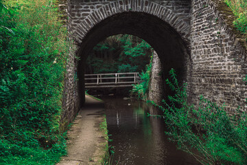 Fototapeta na wymiar a path and a river under a stone bridge