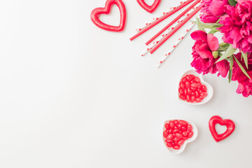 Flat lay valentines day frame with red peonies, candies and red hearts on a white background. Valentines day banner with copy space