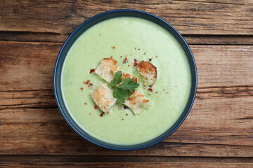 Delicious asparagus soup with croutons on wooden table, top view