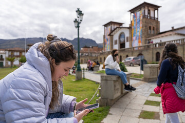 Fototapeta premium Young woman using the mobile while sitting on an ur¡ban park